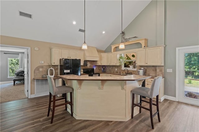 kitchen with high vaulted ceiling, visible vents, black appliances, and custom range hood