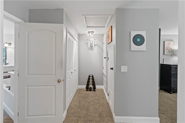 corridor with carpet floors, attic access, and baseboards