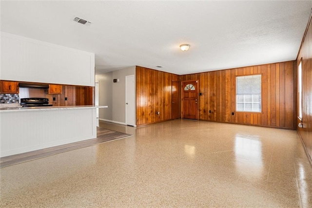 unfurnished living room with wood walls