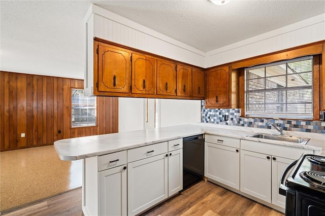 kitchen featuring sink, black appliances, kitchen peninsula, and white cabinets