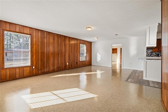 unfurnished room with a textured ceiling and wooden walls