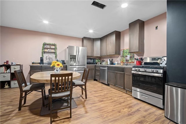 kitchen with appliances with stainless steel finishes, light hardwood / wood-style floors, and dark brown cabinets