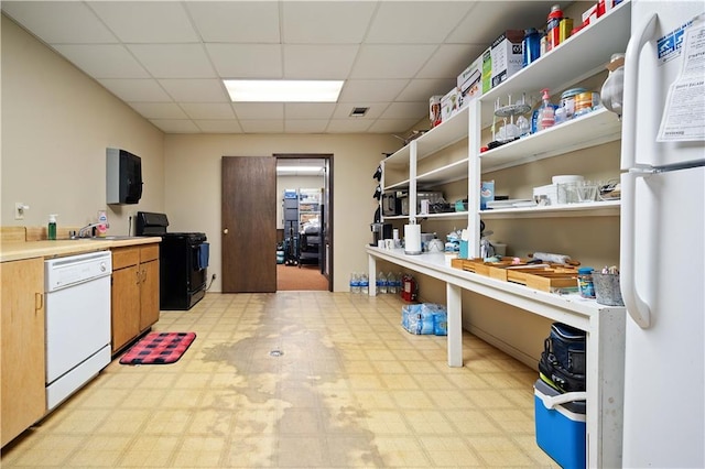 kitchen with a drop ceiling, white appliances, and sink