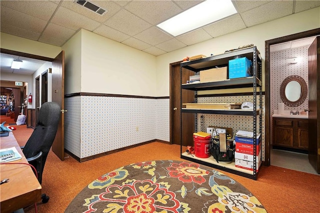 carpeted home office with a drop ceiling