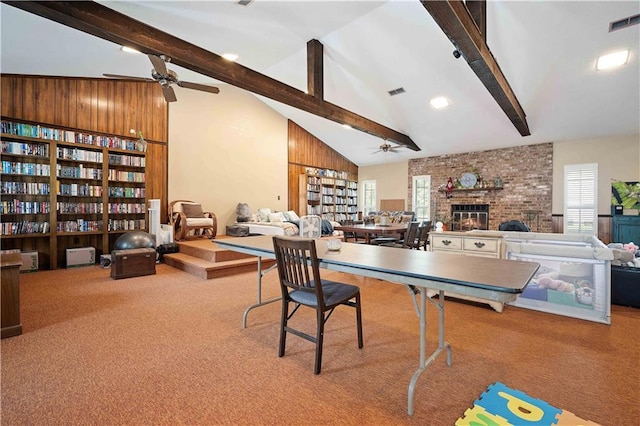 playroom with a brick fireplace, ceiling fan, and beamed ceiling