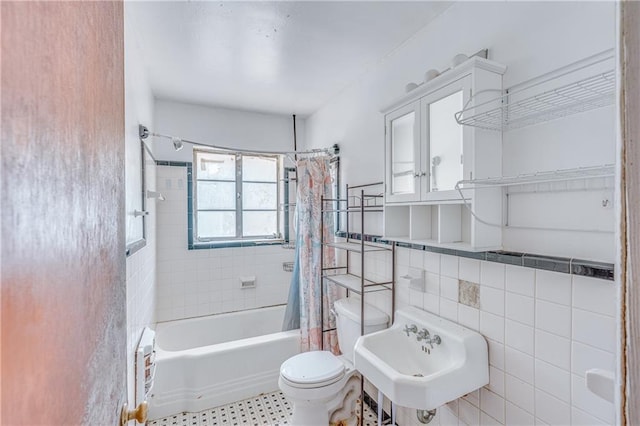 full bathroom featuring tile walls, toilet, shower / bath combo, and a sink