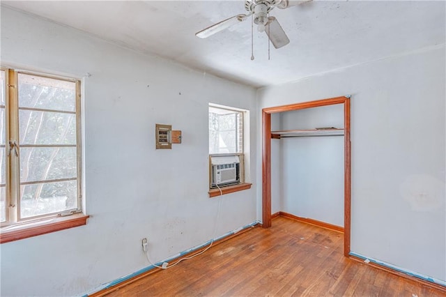 unfurnished bedroom with cooling unit, a ceiling fan, baseboards, a closet, and wood-type flooring