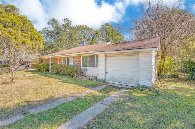 single story home featuring a front yard, brick siding, and driveway