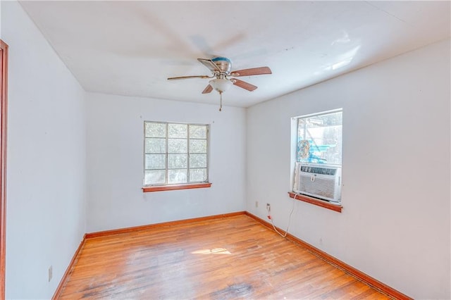 spare room with a ceiling fan, cooling unit, baseboards, and light wood-type flooring