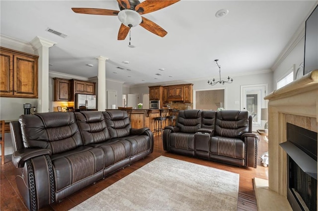 living room featuring decorative columns, wood finished floors, a fireplace with flush hearth, and visible vents