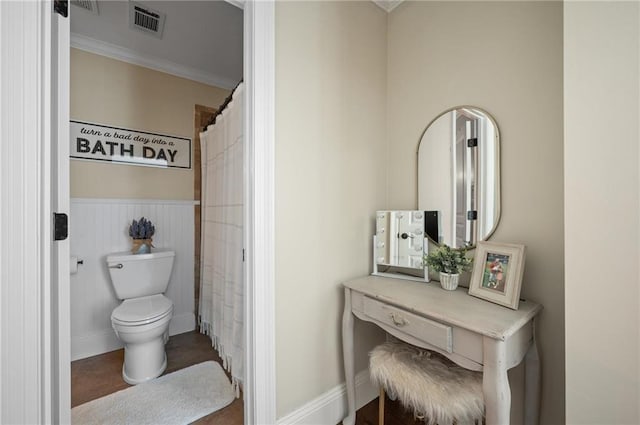 bathroom with toilet, a wainscoted wall, visible vents, ornamental molding, and a shower with curtain