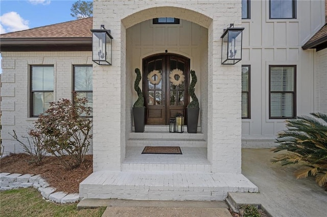 property entrance featuring board and batten siding, brick siding, and a shingled roof