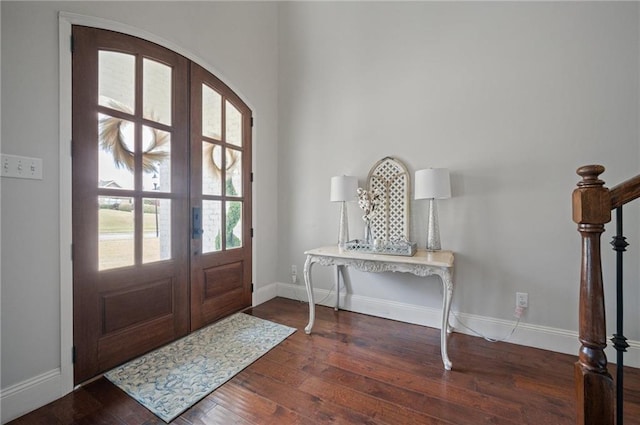 entrance foyer featuring arched walkways, french doors, baseboards, and hardwood / wood-style floors