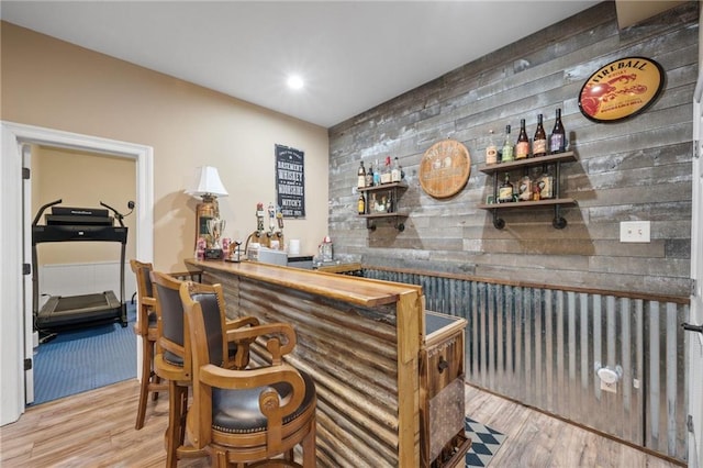 bar featuring an accent wall, recessed lighting, bar, and wood finished floors