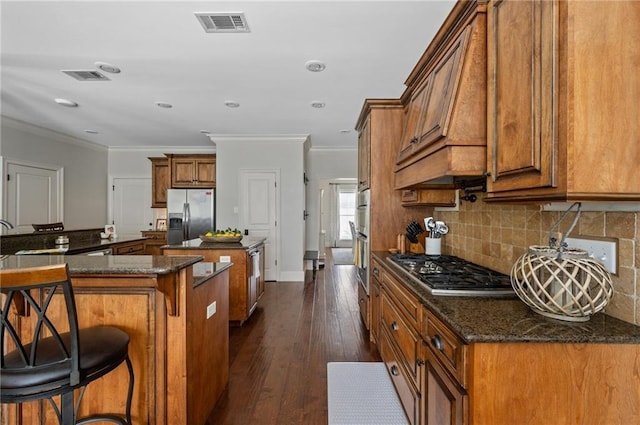 kitchen with appliances with stainless steel finishes, backsplash, a kitchen island, and brown cabinets