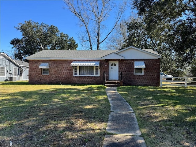 view of front of home featuring a front yard, brick siding, fence, and central air condition unit