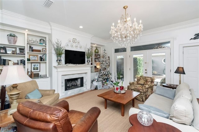 living area featuring crown molding, a premium fireplace, visible vents, french doors, and an inviting chandelier