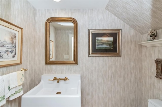 half bath with vaulted ceiling, a sink, and toilet