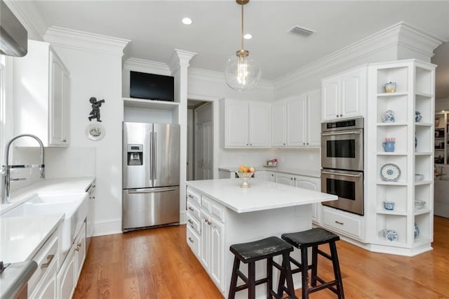 kitchen featuring light wood finished floors, white cabinets, appliances with stainless steel finishes, a center island, and open shelves