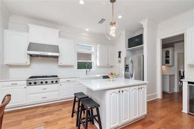 kitchen featuring white cabinetry, a center island, sink, ventilation hood, and appliances with stainless steel finishes