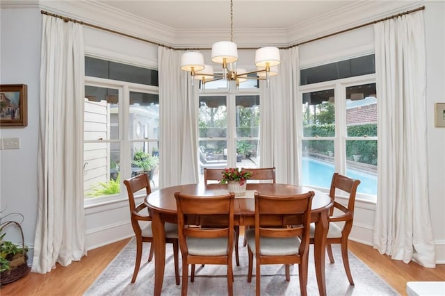 dining area with wood-type flooring, crown molding, a wealth of natural light, and a chandelier