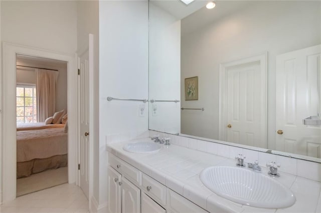 ensuite bathroom with double vanity, a skylight, a sink, and connected bathroom