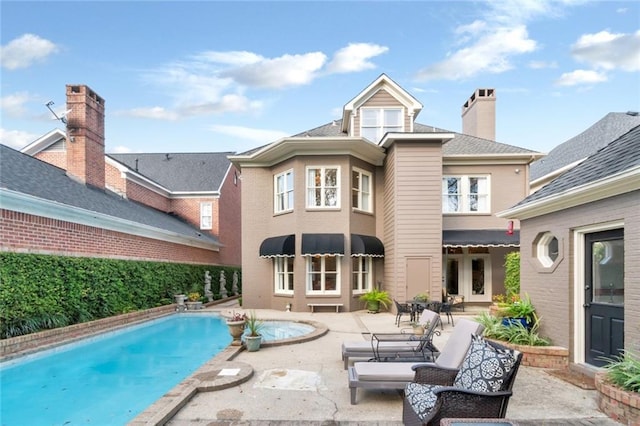 rear view of house featuring a patio area, an outdoor pool, and a chimney