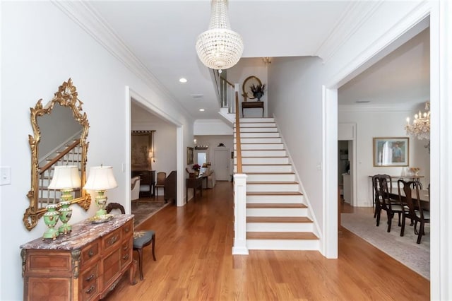 stairway with crown molding, hardwood / wood-style floors, and a chandelier