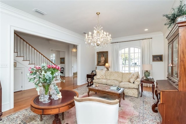 living room with a notable chandelier, light hardwood / wood-style floors, and ornamental molding