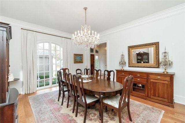 dining area featuring light hardwood / wood-style flooring, ornamental molding, and a notable chandelier