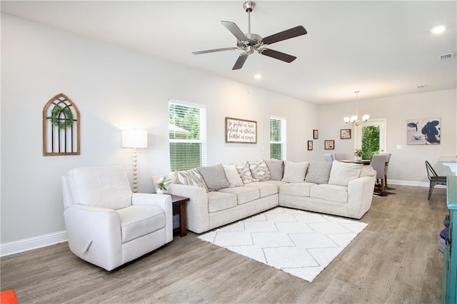 living room featuring ceiling fan with notable chandelier and light wood-type flooring