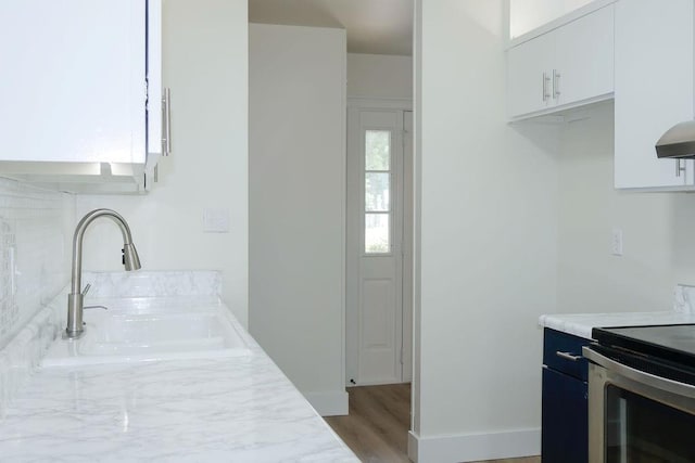 871 Hale Rd, Mobile, AL 36608 - kitchen with stainless steel electric range oven, light countertops, a sink, white cabinets, and wall chimney exhaust hood