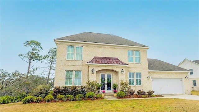 view of front of home featuring driveway, french doors, roof with shingles, a front yard, and an attached garage