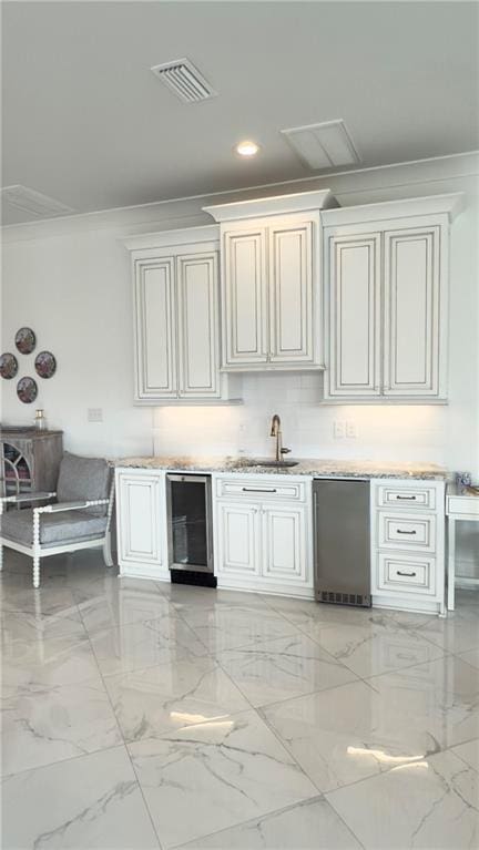 kitchen featuring visible vents, crown molding, wine cooler, light countertops, and a sink