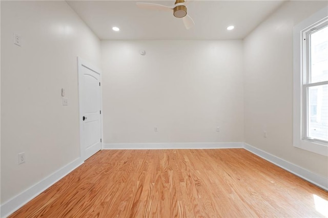 spare room featuring light wood finished floors, a wealth of natural light, ceiling fan, and baseboards