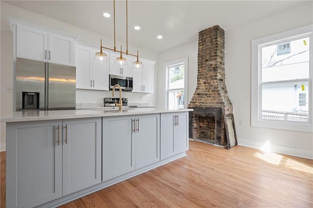 kitchen with light wood-style flooring, recessed lighting, appliances with stainless steel finishes, white cabinetry, and an island with sink