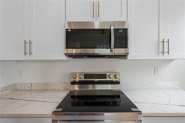 kitchen with white cabinetry, stainless steel appliances, and light stone counters