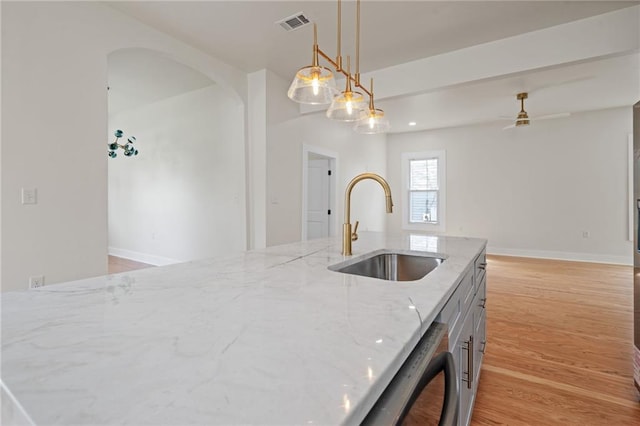 kitchen featuring open floor plan, light wood-type flooring, a sink, visible vents, and light stone countertops