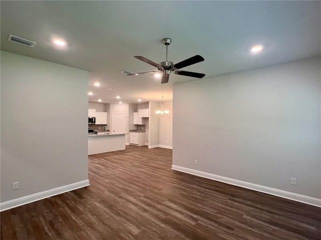 unfurnished living room featuring ceiling fan with notable chandelier and dark hardwood / wood-style flooring