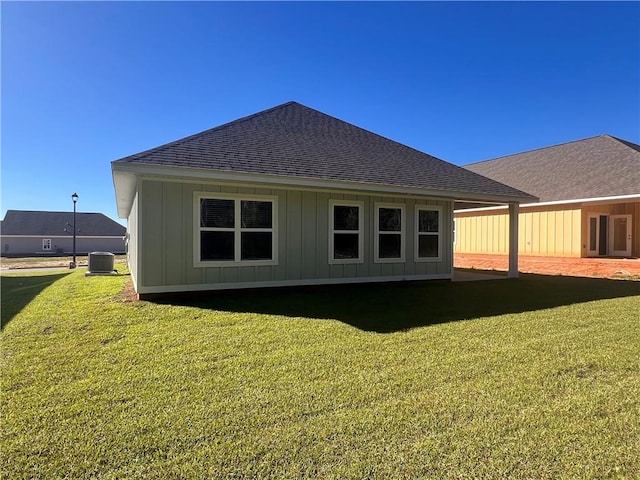 back of house with central air condition unit and a yard