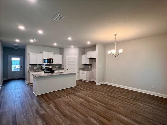 kitchen with a kitchen island with sink, white cabinets, dark hardwood / wood-style floors, light stone counters, and stainless steel appliances