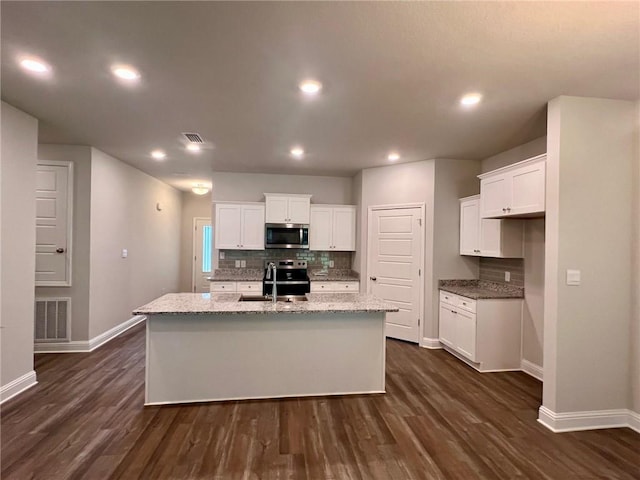 kitchen with a center island with sink, light stone counters, white cabinetry, and sink