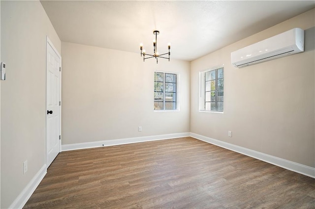 empty room with baseboards, a notable chandelier, wood finished floors, and a wall mounted AC