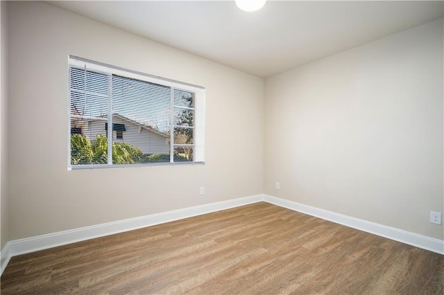 empty room with baseboards and wood finished floors