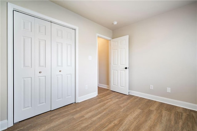 unfurnished bedroom featuring a closet, baseboards, and wood finished floors