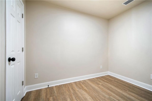 spare room with visible vents, baseboards, and wood finished floors