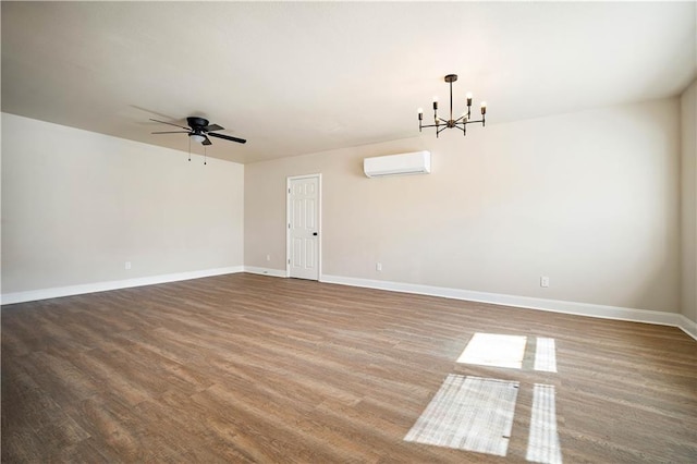 unfurnished room featuring ceiling fan with notable chandelier, a wall mounted air conditioner, baseboards, and wood finished floors