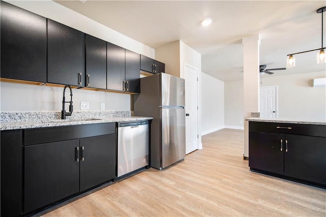 kitchen featuring a sink, stainless steel appliances, light wood-style floors, and dark cabinetry