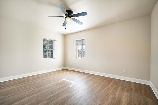 spare room featuring a ceiling fan, baseboards, and dark wood-style flooring