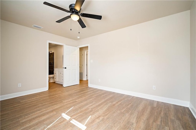 unfurnished room with visible vents, light wood-style flooring, a ceiling fan, and baseboards